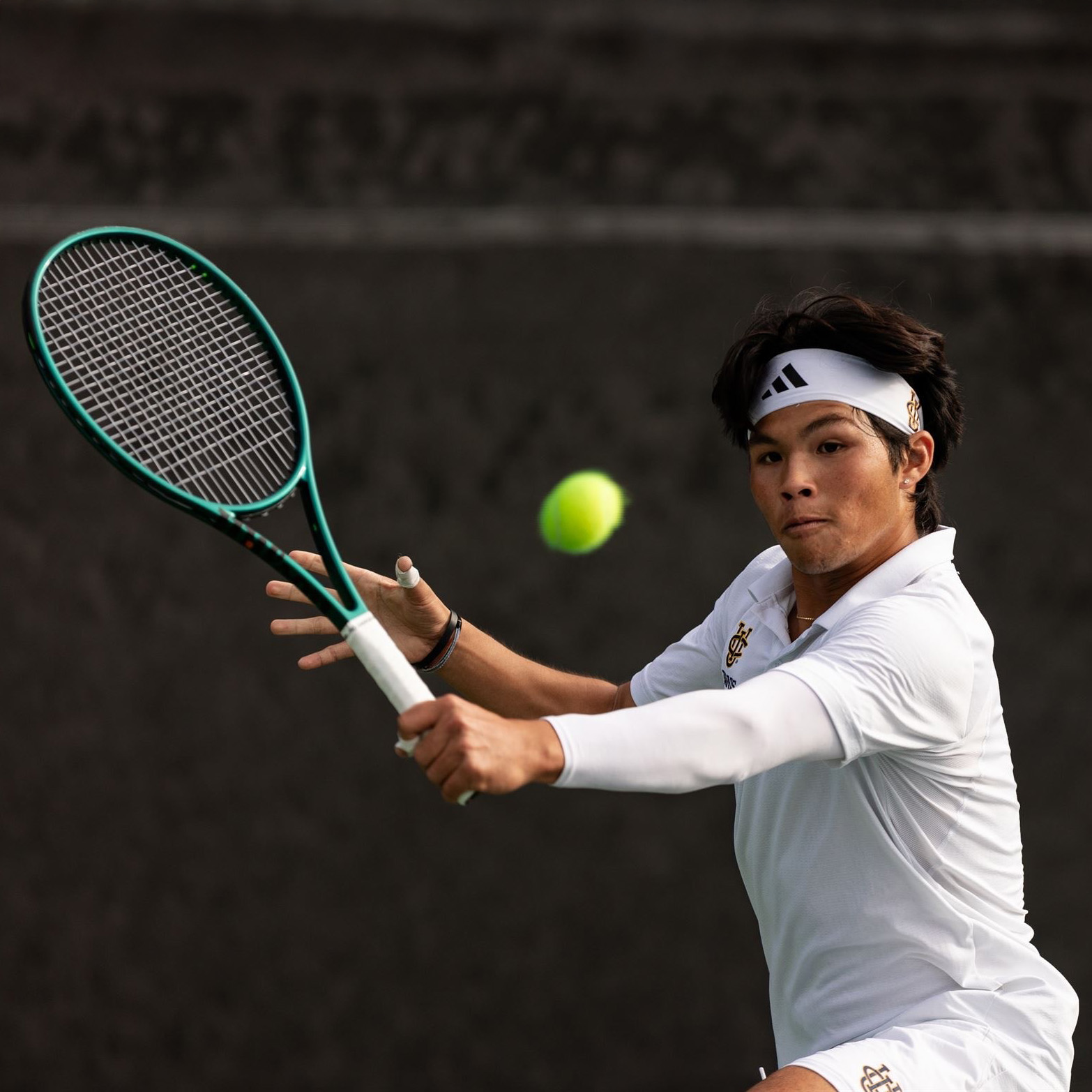 Andy Nguyen hitting a backhand during a tennis match while playing for the UCI men's tennis team.