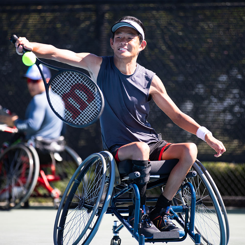 Asian man in blue wheelchair playing wheelchair tennis in Southern California.
