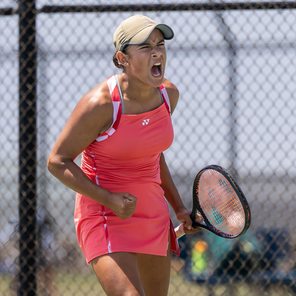 Kiana Huerta fist pumping wearing a neon pink tennis outfit during a match at Junior Sectionals.