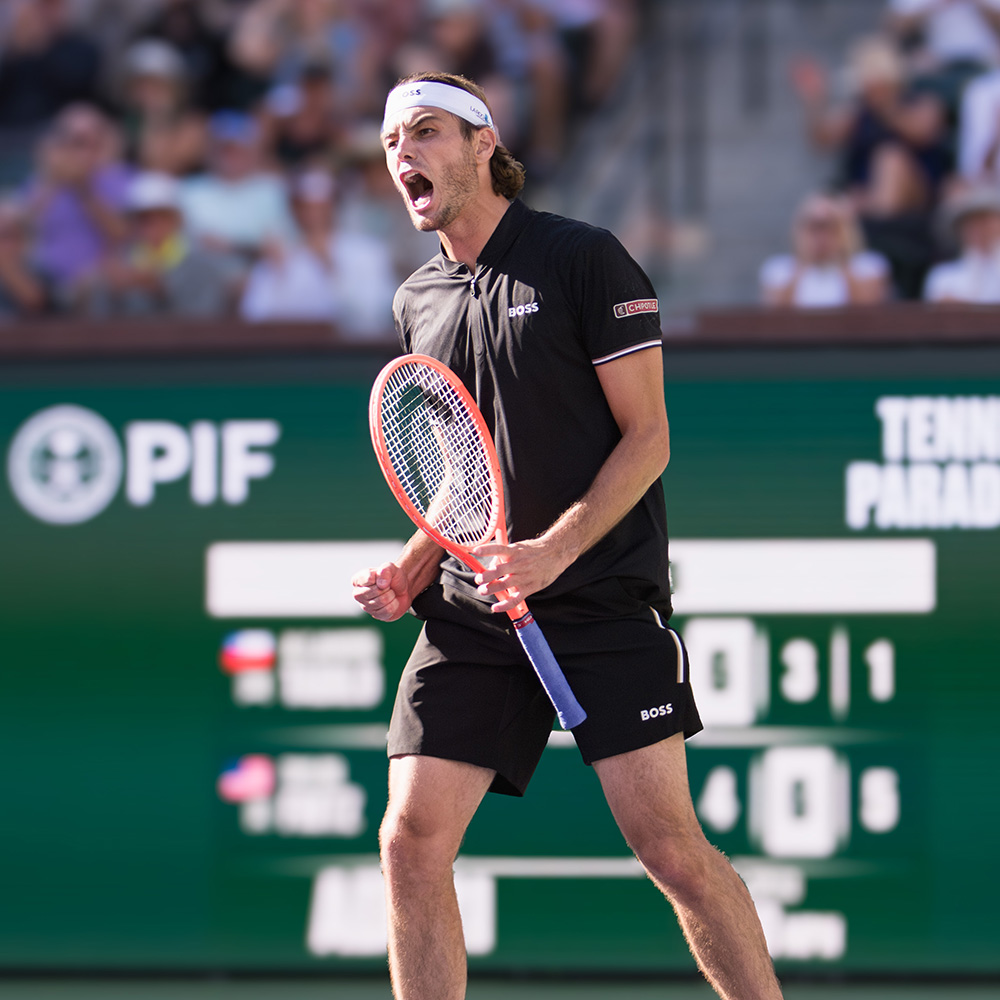 Taylor Fritz raises his orange tennis racquet in triumph, celebrating a victory at the 2025 BNP Paribas Open.