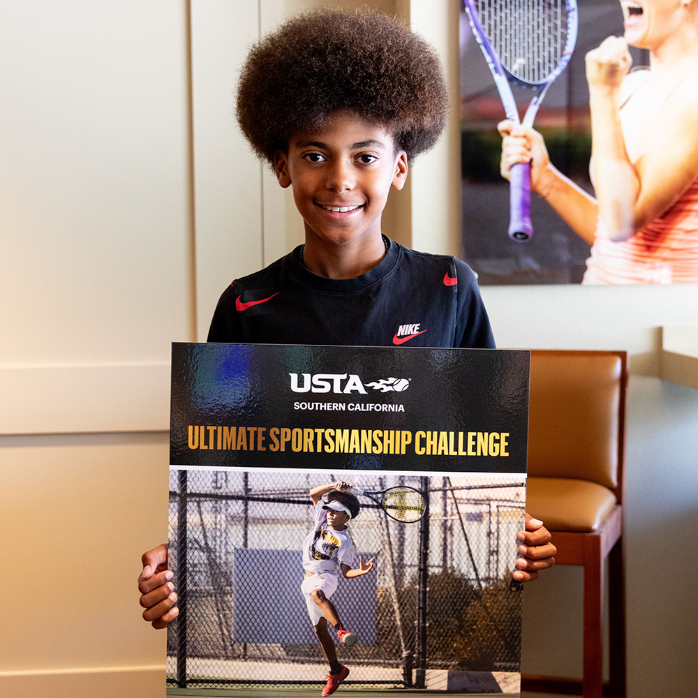Jaden Joyner holds a poster and smiles after winning the Ultimate Sportsmanship Challenge in the USTA Southern California suite at the 2025 BNP Paribas Open.