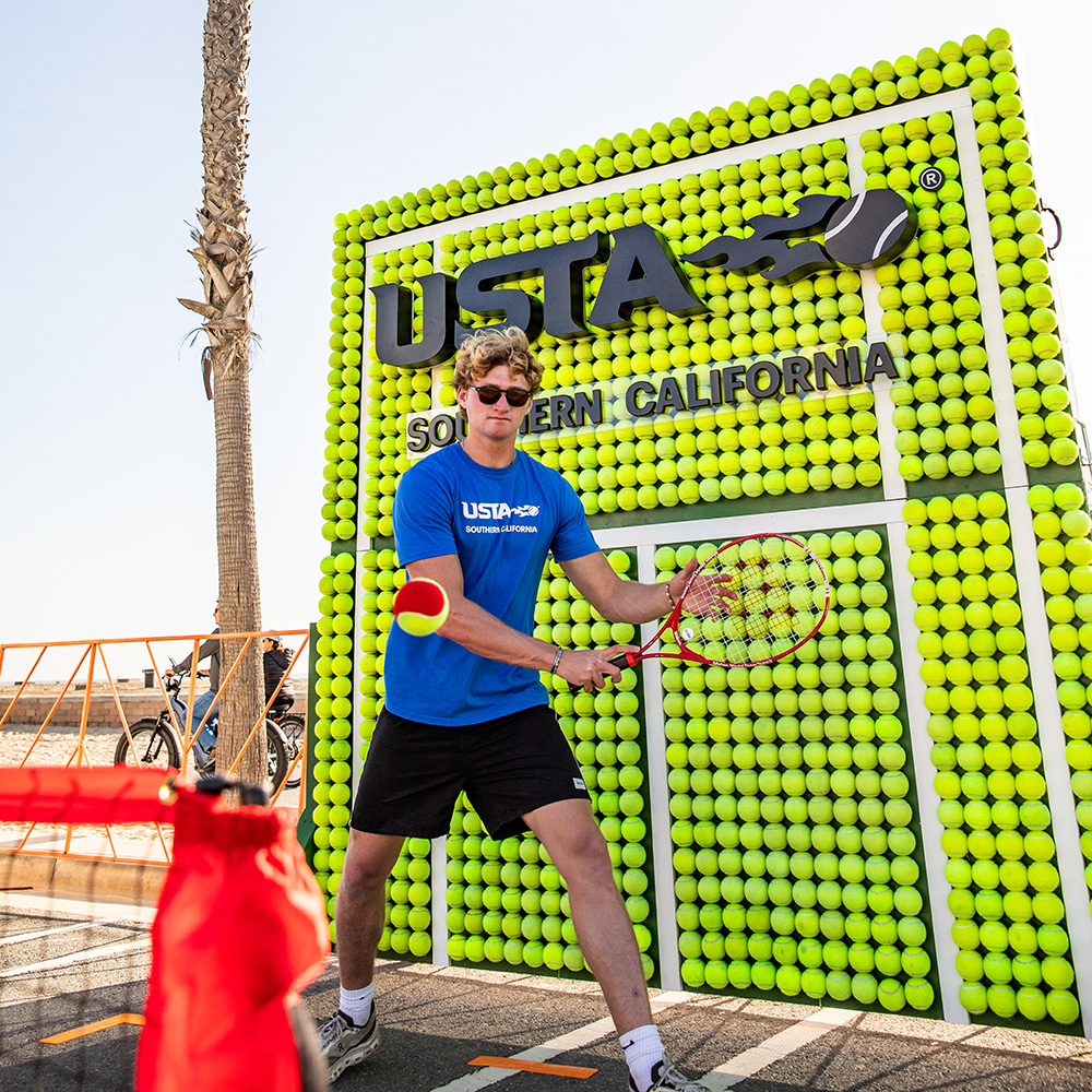 Julien Grigaux plays red ball tennis with attendees during a USTA SoCal field marketing activation at the Surf City Marathon